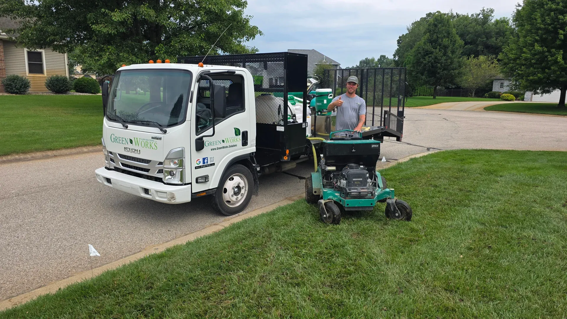 A GreenWorks technician giving a thumbs up beside a company truck