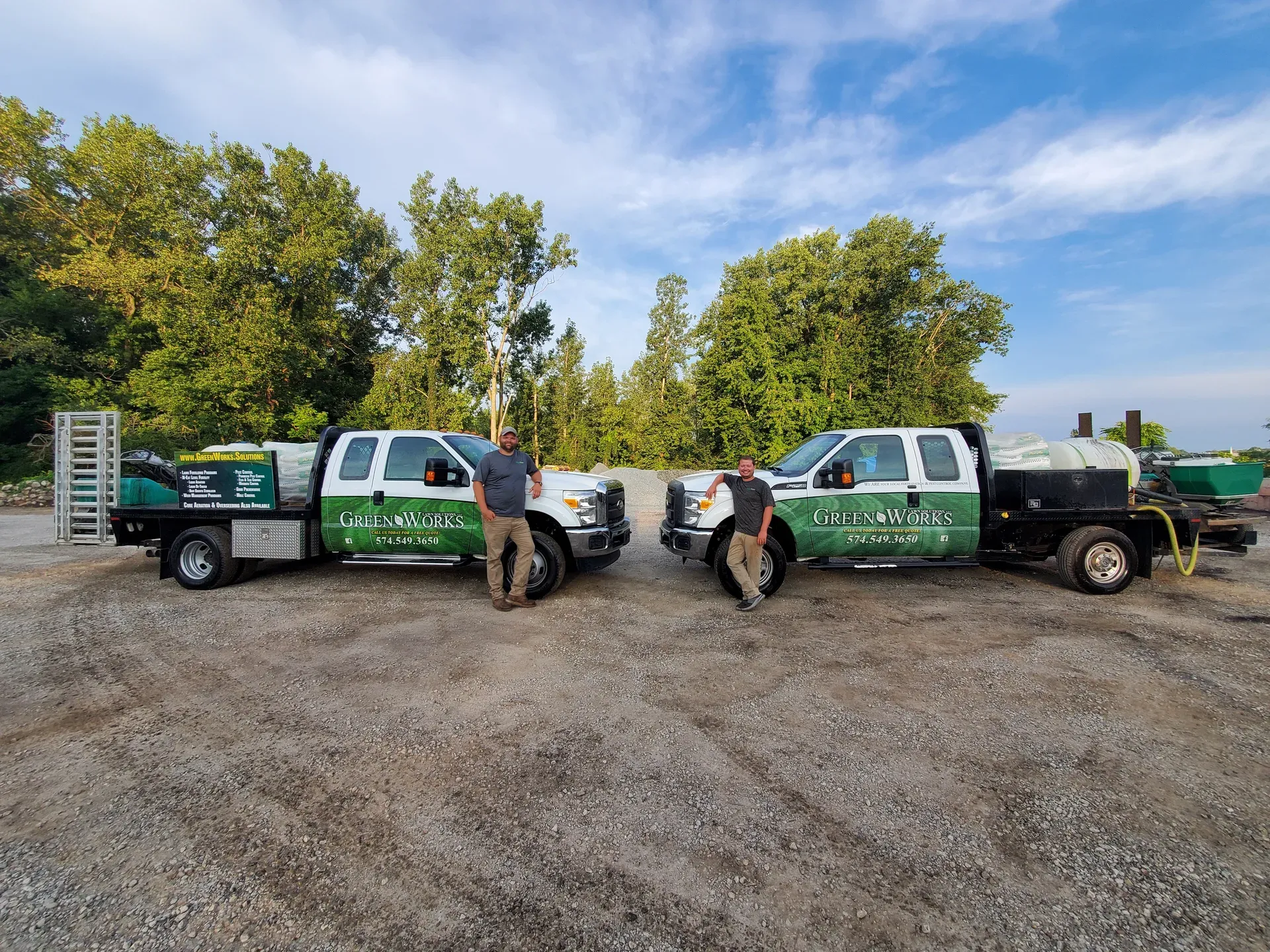 Steven and Alex standing between two GreenWorks trucks loaded with equipment