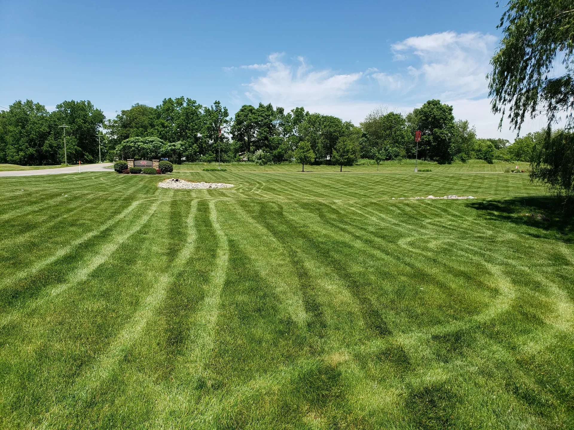 A wide striped lawn in front of the KREMC building on a clear day